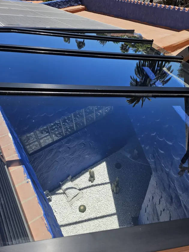 The same skylight cleaned, reflecting the palms and the sky