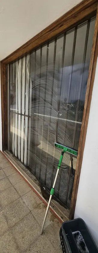 Barred window mid-clean, with soap and squeegee